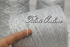 a hand is pointing to the word filati chrome on a roll of yarn