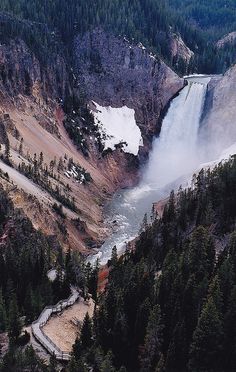 an aerial view of a waterfall in the middle of a forest with snow on it