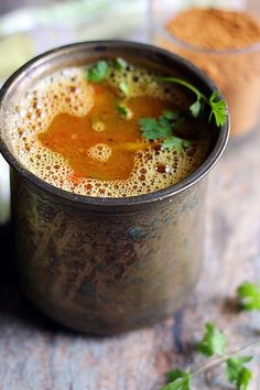 a metal cup filled with liquid and garnished with cilantro