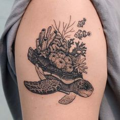 a woman's arm with a tattoo of a turtle and corals on it