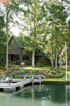 a dock sits in front of a house on the water's edge, surrounded by trees