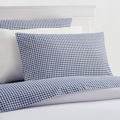 a bed with blue and white gingham sheets, pillows and pillowcases