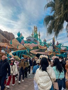 many people are walking around in front of a float at the amusement park on a cloudy day