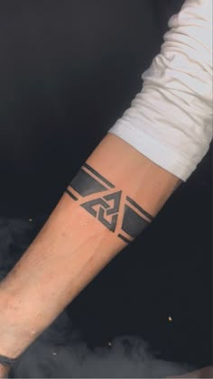 a man's arm with a black and white tattoo design on the left forearm