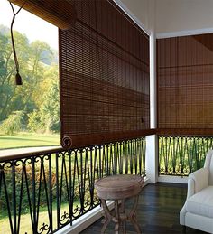 the balcony is decorated with wooden blinds and wrought iron railings, along with a white chair