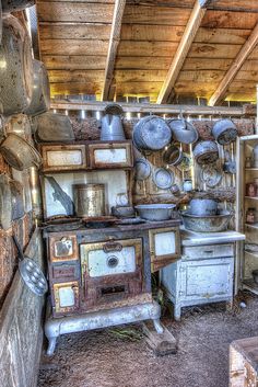 an old kitchen with pots and pans hanging from the ceiling