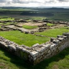 an aerial view of a stone structure in the middle of a field