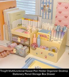 a desk with many different items on it and a person's hand holding a pen