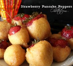 strawberry pancake poppers on a white plate with strawberries in the middle and another dessert behind them