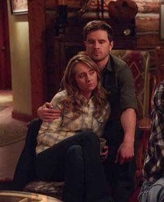 two men and a woman sitting on chairs in a living room, one is holding her arm around the other's neck