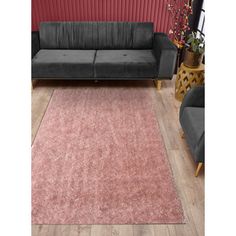 a living room with a couch, chair and rug on the floor in front of a red wall