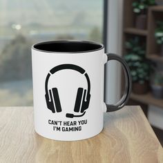 a white and black coffee mug with headphones on it that says, can't hear you i'm gaming