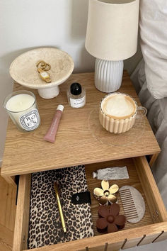 an open drawer on a bed with makeup and other items in the drawer next to it