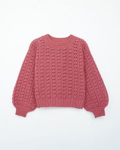 a pink sweater with holes on the front and back, sitting on a white surface