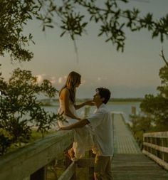 a man standing next to a woman on top of a wooden bridge