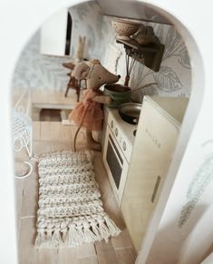 a doll house kitchen with an oven, sink and rugs on the floor in front of it