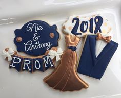 two decorated cookies on top of a white plate with blue and gold decorations in the shape of bride and groom's names