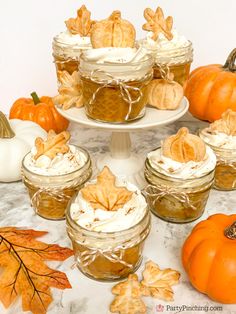 there are many desserts on the table with pumpkins and leaves in the background