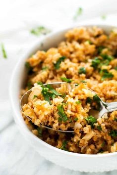 a white bowl filled with rice and garnished with cilantro