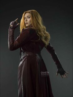 a woman with long red hair in a black dress and gloves is posing for the camera