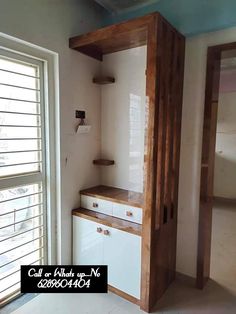 an empty room with white cupboards and wooden shelves next to a large open window