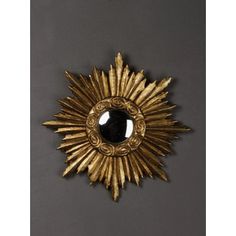 a gold sunburst with a black stone in the center on a gray background