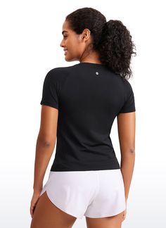 a woman in white shorts and a black shirt is looking at the back of her body