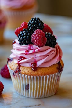 a cupcake with raspberries and blackberries on top