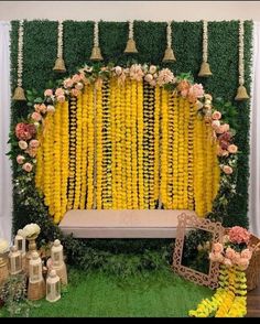 a yellow and white backdrop with flowers on the wall, two gold bells hanging from them