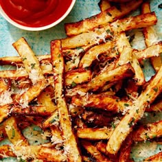 french fries with parmesan cheese and ketchup on a blue tablecloth