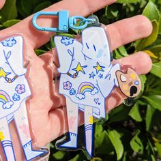 two keychains with cartoon characters on them are held in someone's hand