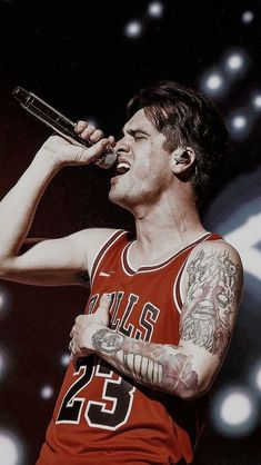 a man with tattoos on his arm singing into a microphone