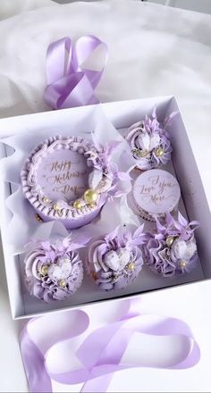 an open box with some cupcakes in it and purple flowers on the inside