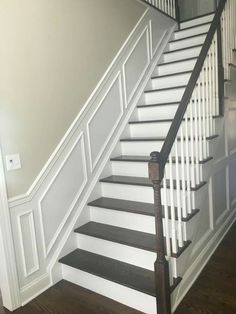 a white staircase with black handrails and wood flooring in a home's entryway