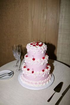 a pink cake sitting on top of a table next to a wine glass and fork