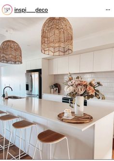 a kitchen with white counter tops and wooden stools next to an open floor plan