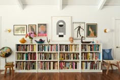 a book shelf filled with lots of books next to a wall full of framed pictures