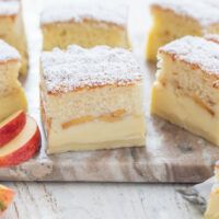 several pieces of cake sitting on top of a wooden cutting board next to an apple