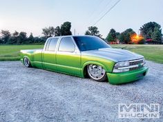 a green truck parked on top of a gravel road