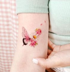 a woman's arm with a butterfly and flowers tattoo on the left side of her arm