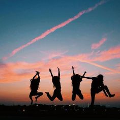 three girls jumping in the air at sunset