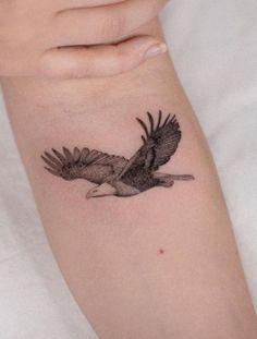 a woman's arm with a bird tattoo on it