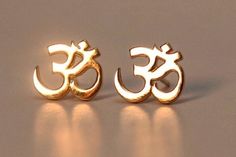 Our earrings are made from 100% solid and pure metals, cast in New York.  The gold stud earrings with diamonds come in 14k gold: yellow, rose gold available.  .9 centimeters wide  .1 centimeters thickness / gage secure solid gold push backs Delicate and symmetrical design of a sacred symbol in the Sanskrit / Yoga tradition. The Om symbol is sacred and holy to millions of people. As a Yoga student and teacher, and student of Sanskrit, I adore this symbol and meditate on it.  The meaning of Om is Rhinebeck Ny, Teacher And Student, Things I Need To Buy, Symmetrical Design, Om Symbol, Sacred Symbols, Gold Stud Earrings, Gold Stud, Sanskrit