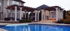 an outdoor swimming pool surrounded by stone steps and pergolated arbors with seating area