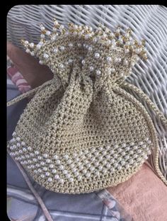 a crocheted purse sitting on top of a bed next to a pink pillow