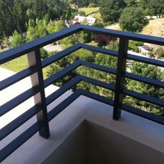 a balcony with black railings and trees in the background, looking down at a valley