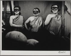 three women with masks on their faces are standing in front of a mirror and looking at the camera