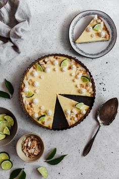 there is a pie on the table with limes and other toppings around it