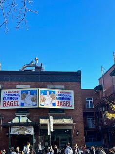 people are walking in front of the famous bagel shop on a sunny day with blue skies