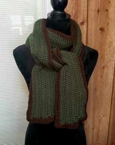 a green and brown knitted scarf on a mannequin